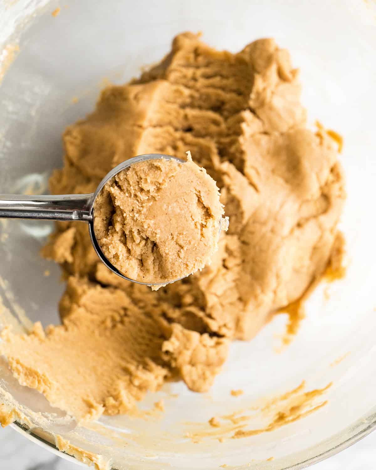 making Peanut Butter Blossoms recipe in a standing mixer - a cookie scoop portioning out the chilled dough