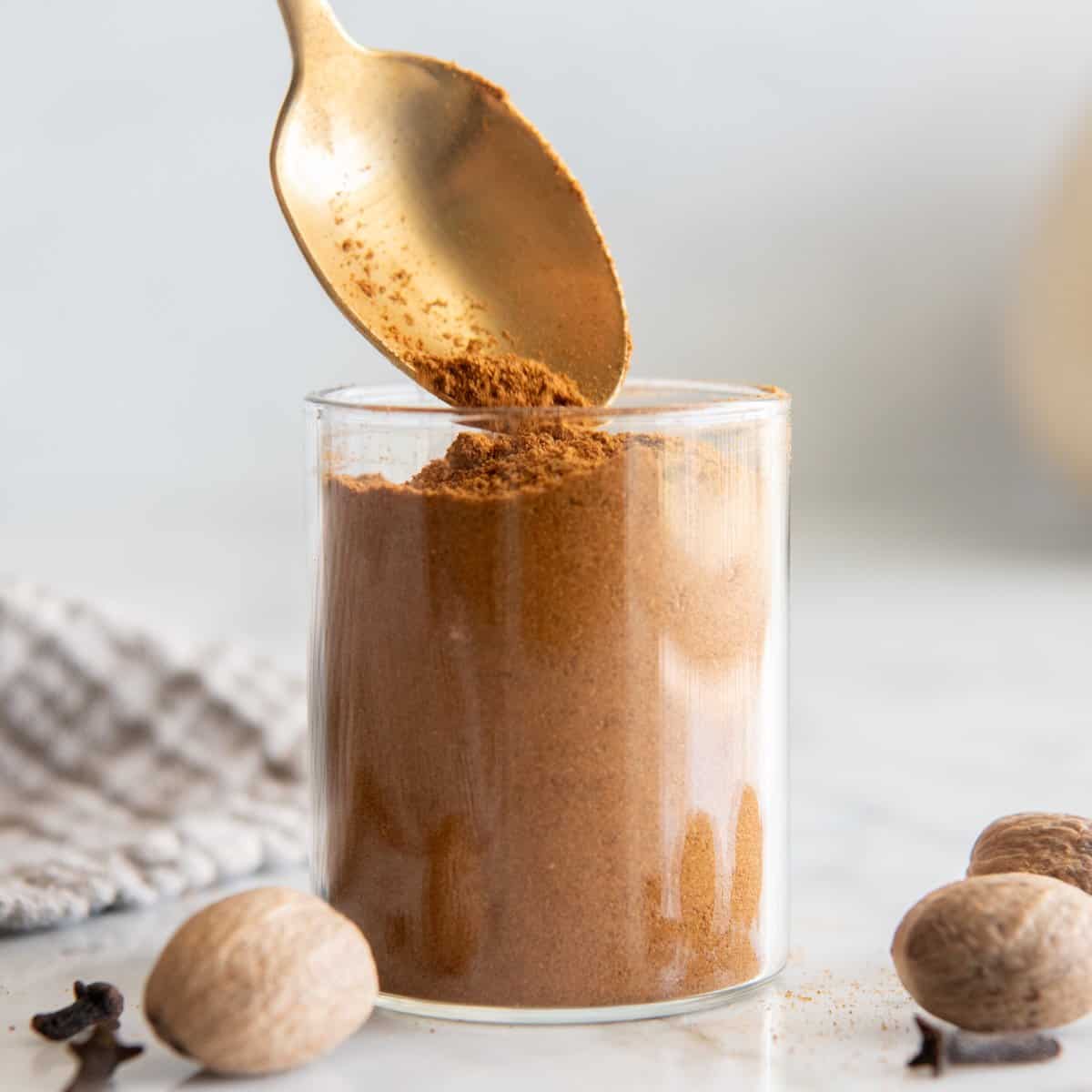 homemade pumpkin pie spice being spooned into a glass jar