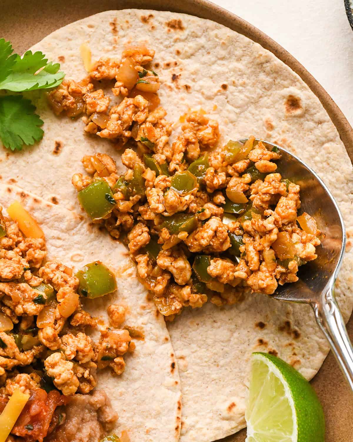a spoon scooping Ground Turkey Taco meat onto a tortilla